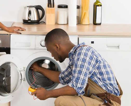 TechSmith technician repairing a washing machine in a Nairobi home